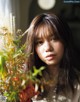 A woman sitting in front of a vase of flowers.