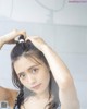 A woman in a black and white bathing suit brushing her hair.