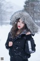 A woman in a black jacket with a fur hood in the snow.