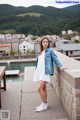 A woman in a white dress and a denim jacket posing for a picture.