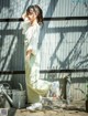 A woman leaning against a metal wall with her hands on her head.