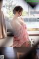 A woman in a pink kimono sitting on a window sill.