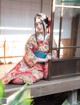 A woman in a kimono sitting on a wooden bench.