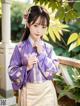 A woman in a purple and white hanbok posing for a picture.