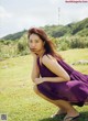 A woman in a purple dress crouching on the grass.