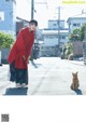 A woman in a red sweater standing next to a cat.