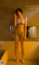 A woman in a bikini standing in a bathroom.