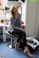 A woman sitting on a stool in front of a closet.