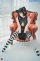 A woman sitting on a red chair wearing black and white striped stockings.