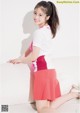 A young woman in a white shirt and pink skirt posing for a picture.